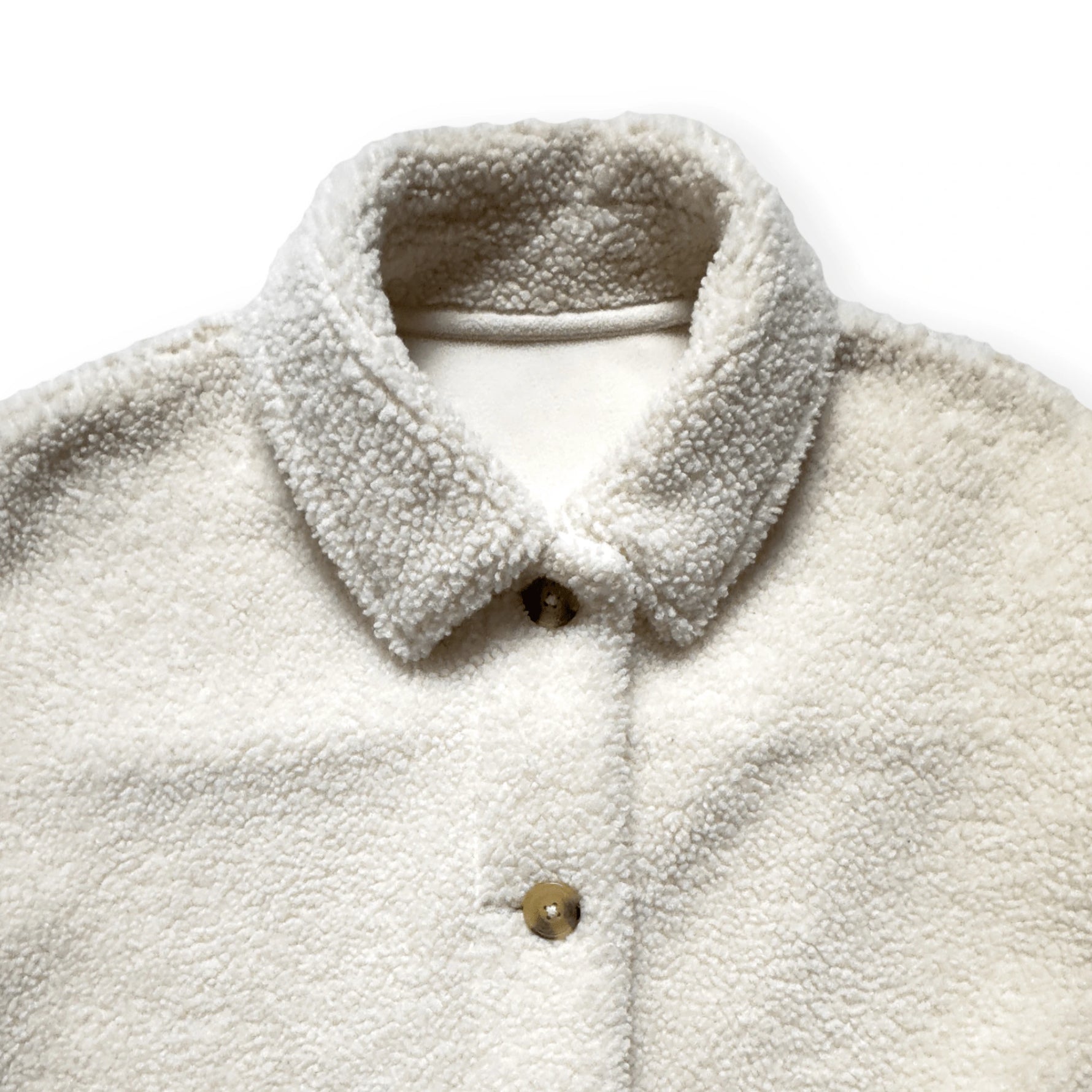 Close-up van de kraag en zachte teddytextuur van een pre-loved Uniqlo overshirt in ecru